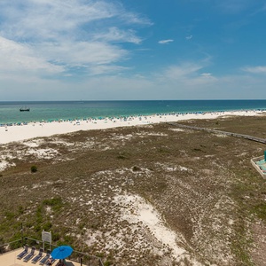 Stunning view of the beach and turquoise gulf waters, featuring a pool area and a winding path to the shore