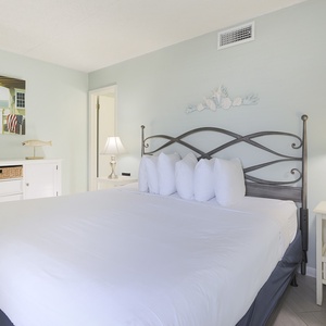 This bedroom features a comfortable bed with plush pillows, soft lighting, and coastal decor for a relaxing getaway