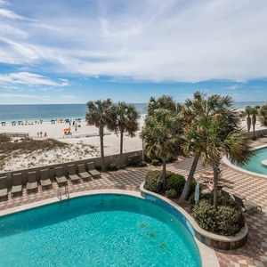 This inviting space features a stunning beachfront view, with a sparkling pool and lush palm trees creating a perfect getaway