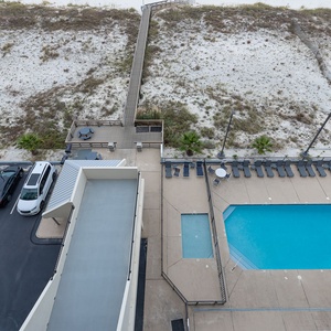 Balcony view of the inviting pool area surrounded by lounge chairs and a scenic pathway leading to the pristine beach