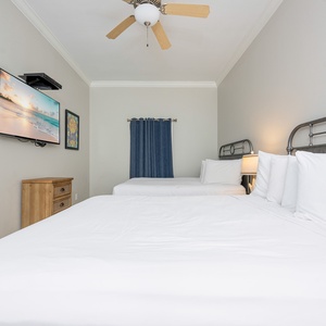 Relax in this inviting guest room featuring two queen beds, a mounted TV, and cheerful decor for a restful stay