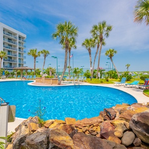 Take a refreshing dip in the pool surrounded by palm trees and lounge chairs, perfect for unwinding after a day at the beach