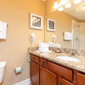 This bathroom features a stylish granite countertop, elegant cabinetry, and plush towels for a relaxing retreat