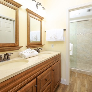 The master bathroom features elegant wooden cabinetry, dual sinks, and a glass-enclosed shower for a refreshing retreat