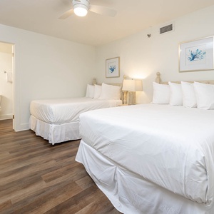 Relax in this guest bedroom featuring two double beds, soft linens, and a warm ambiance for restful nights