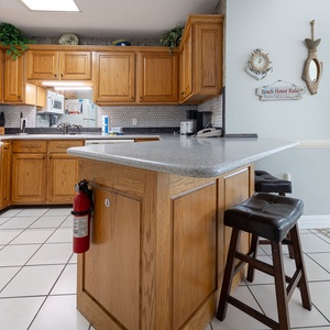 Warm wood cabinetry complements the granite countertop in this inviting kitchen area, featuring a breakfast bar with seating