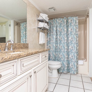 Guest bathroom featuring a granite countertop, floral shower curtain, and neatly arranged towels for a refreshing experience