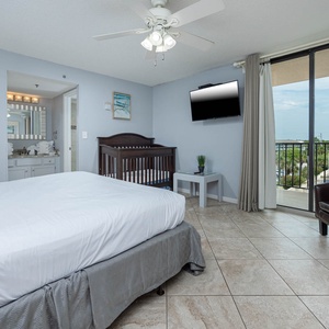 The cozy master features a plush king bed, infant crib, wall-mounted TV, and a charming view from the balcony