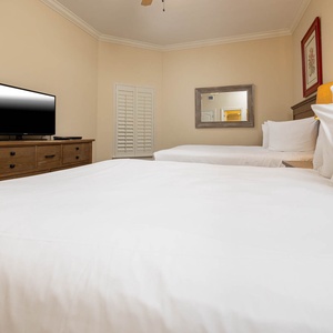 This guest bedroom features two comfortable queen beds, a TV for entertainment, and a warm, inviting atmosphere