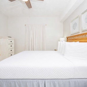 Relax in this inviting guest room featuring a queen bed, soft linens, and coastal artwork that enhances your comfort