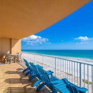 Relax on vibrant blue chairs on the balcony, soaking in the expansive views of the tranquil beachfront shoreline