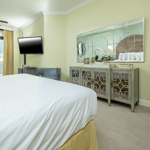 The master bedroom features a large TV, elegant cabinetry, and beachfront views from the master suite