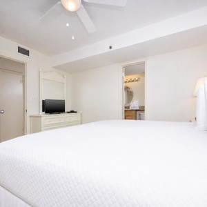 This bedroom features a plush king bed, a flat-screen TV, and an adjoining bathroom with elegant granite countertops