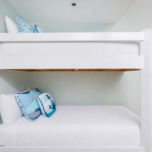 Bright and cheerful twin bunk beds with nautical-themed pillows, perfect for kids enjoying a beach getaway
