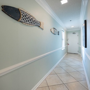 Enter a welcoming hallway adorned with coastal fish decor, leading to your relaxing retreat on the beach