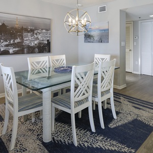 The dining area features a glass-top table surrounded by white chairs, complemented by stylish decor