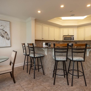 The kitchen features granite countertops, stainless appliances, and a cozy dining area with a glass table for shared meals