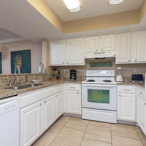 This kitchen features white cabinetry, granite countertops, and modern appliances, perfect for preparing meals in style