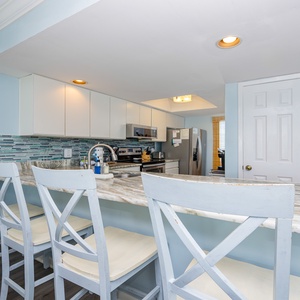 This modern kitchen features sleek stainless appliances, a stylish backsplash, and a breakfast bar perfect for casual dining
