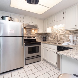The kitchen features stainless appliances, granite countertops, coffee maker, and a stylish backsplash