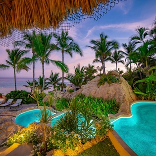 Patio with pool and beachfront view during sunset