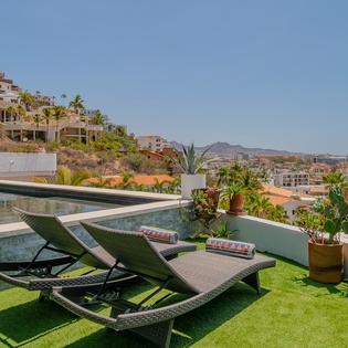 Lounge on your private terrace with stunning hillside and mountain views. Enjoy the pool, lush greenery, and sunny skies in this serene outdoor retreat.