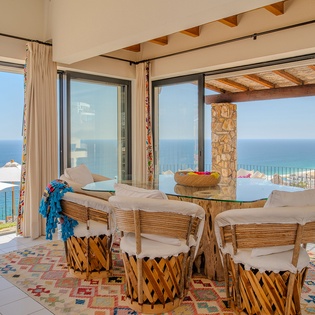 Your ocean-view dining space frames endless blue horizons through floor-to-ceiling windows, creating an unforgettable backdrop for memorable meals.