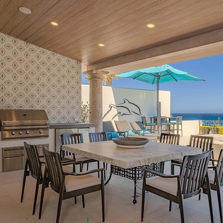 Beachfront covered patio features a stunning ocean view, complete with a built-in grill, large dining table, and outdoor seating—perfect for entertaining and savoring seaside meals.