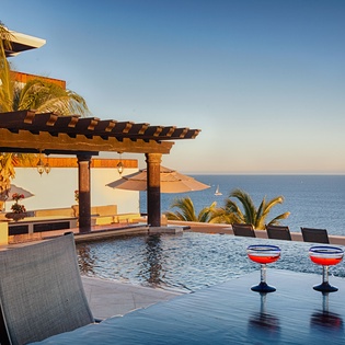 Stunning infinity pool overlooking the endless ocean, framed by swaying palms and a shaded pergola. Perfect for sipping cocktails as sailboats drift by at golden hour.