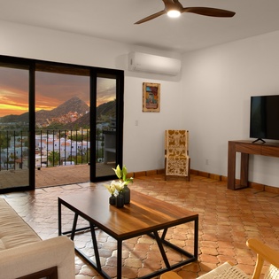 Unwind in your modern living space with stunning sunset views through floor-to-ceiling windows, complete with comfortable seating and entertainment.