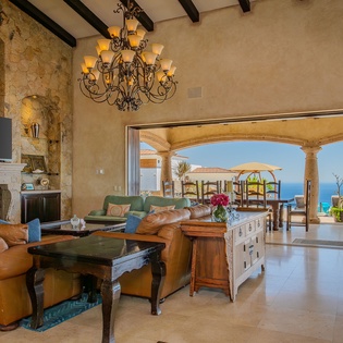 Relax in your elegant living space where rustic charm meets luxury, featuring a stunning fireplace and seamless flow to your private oceanfront terrace.
