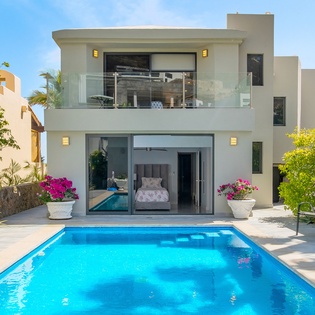 Modern luxury villa with sparkling private pool surrounded by tropical gardens and contemporary architecture.