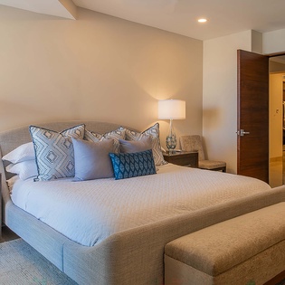 Sink into plush linens and layered pillows in your serene bedroom, where soft lighting and coastal-inspired blues invite restful nights and peaceful mornings.
