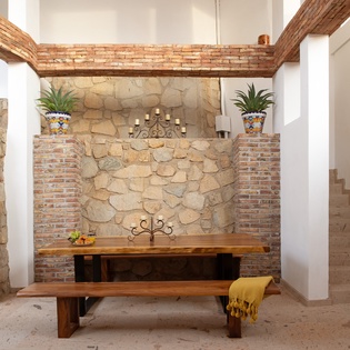 Relax in your charming dining nook with rustic stone walls, exposed beams, and authentic Mexican-style decor creating a warm, inviting atmosphere.
