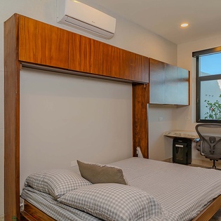 You'll appreciate the smart design of this guest room, where a Murphy bed maximizes your space while warm wood tones and modern touches create a comfortable retreat with a built-in workspace and ocean views.
