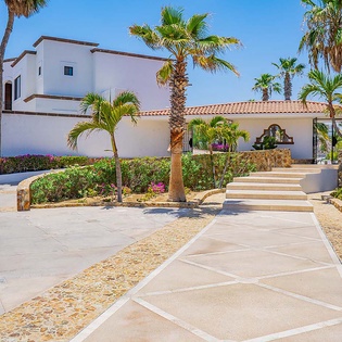 Elegant Spanish-style villa with terracotta roofing, lush tropical palms, and colorful gardens creates a tranquil, sunlit retreat perfect for your getaway.