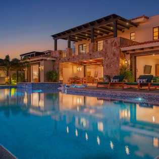 Stunning villa exterior with pool area during golden hour twilight showcasing elegant architecture and outdoor entertaining spaces.