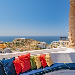Panoramic coastal views stretch before you from this stunning terrace, where colorful cushions invite relaxation amid Mediterranean charm.