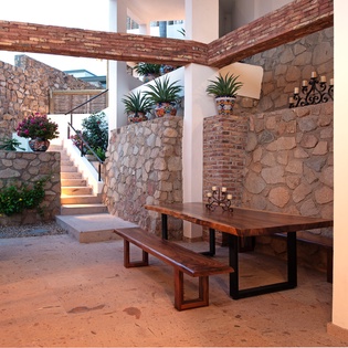 Step into your private courtyard where rustic stone walls and vibrant blooms create a peaceful dining retreat under the stars.