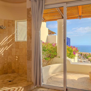 Step out from your luxurious bathroom to a private terrace with vibrant flowers and stunning ocean views stretching to the horizon.