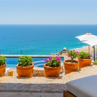 Breathtaking ocean views from your private terrace with infinity pool, colorful planters, and comfortable seating for ultimate relaxation.