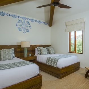 Drift off peacefully in your spacious twin bedroom, where handcrafted wood beds and charming blue accents create a serene sanctuary for restful nights.