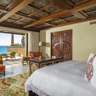 Wake to stunning sea views from your luxurious bedroom featuring an ornate coffered ceiling and vibrant Mexican-inspired decor.