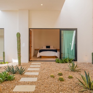 Your private bedroom opens to a stunning desert garden courtyard with towering cacti and smooth stone pathways creating a serene desert oasis.