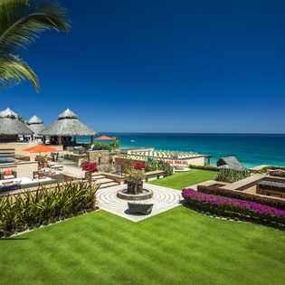 Luxury beachfront resort featuring pristine gardens, oceanfront pool, and traditional thatched palapas overlooking turquoise waters.