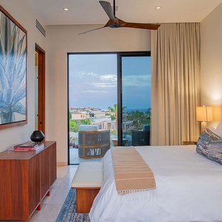 Wake up to breathtaking ocean views from your serene bedroom retreat, where crisp linens and modern comfort meet coastal tranquility through floor-to-ceiling windows.