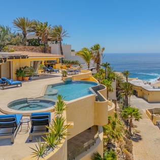 Stunning beachfront villa with infinity pool, hot tub, and panoramic ocean views surrounded by swaying palms.