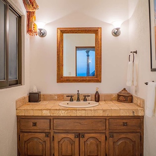 Step into your private bathroom where rustic charm meets coastal elegance—featuring warm wood cabinetry, hand-painted tile, and thoughtful touches that make you feel right at home.