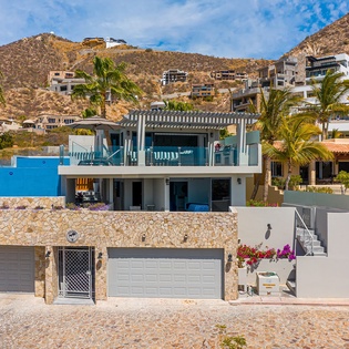 Modern hillside property featuring contemporary architecture with mountain backdrop and tropical landscaping in scenic coastal setting.