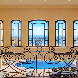 View of poolside and ocean from the interior of villa